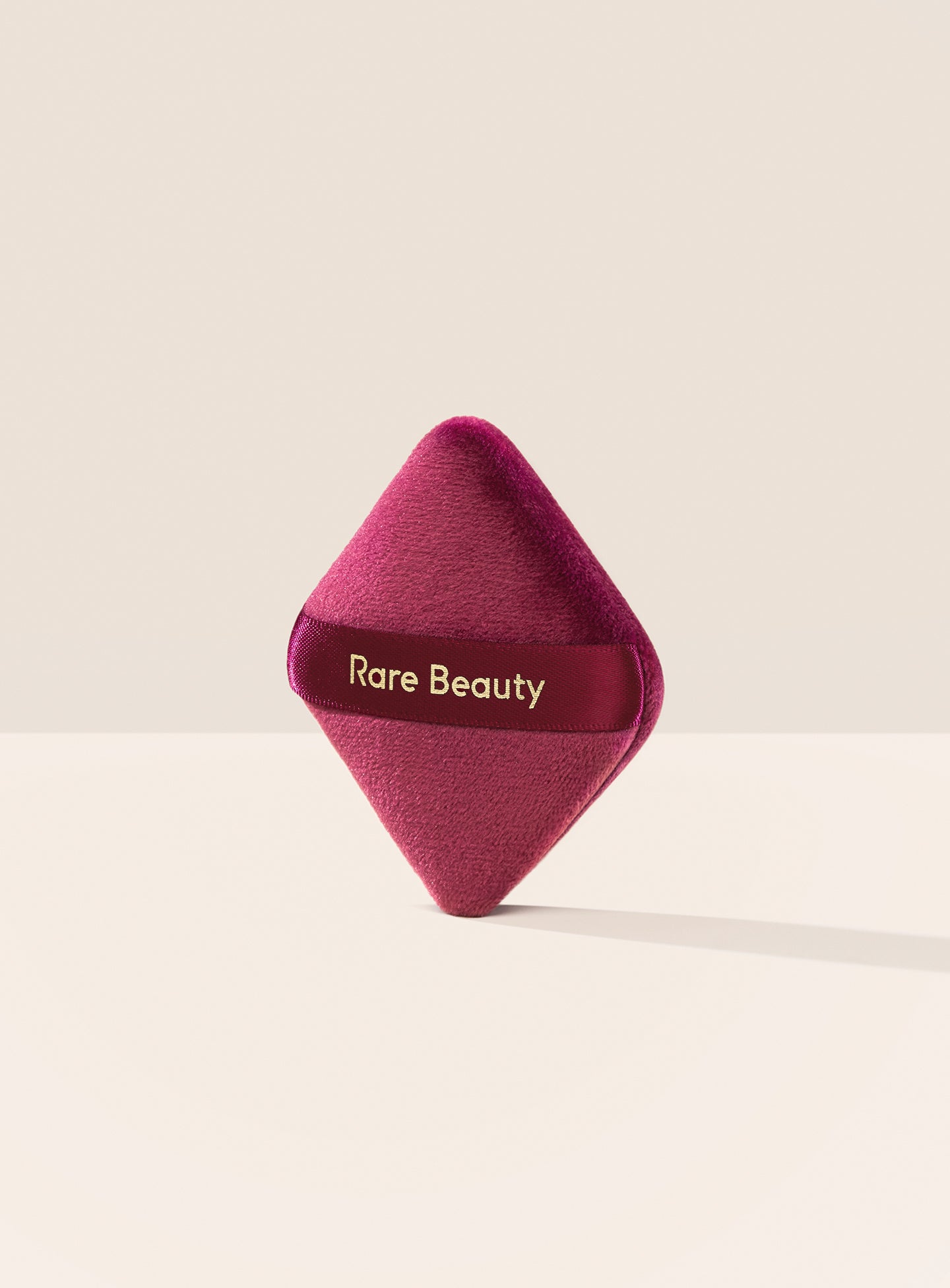 Rare Beauty's Soft Touch Powder Puff, a diamond-shaped velvety powder puff for precise powder application.